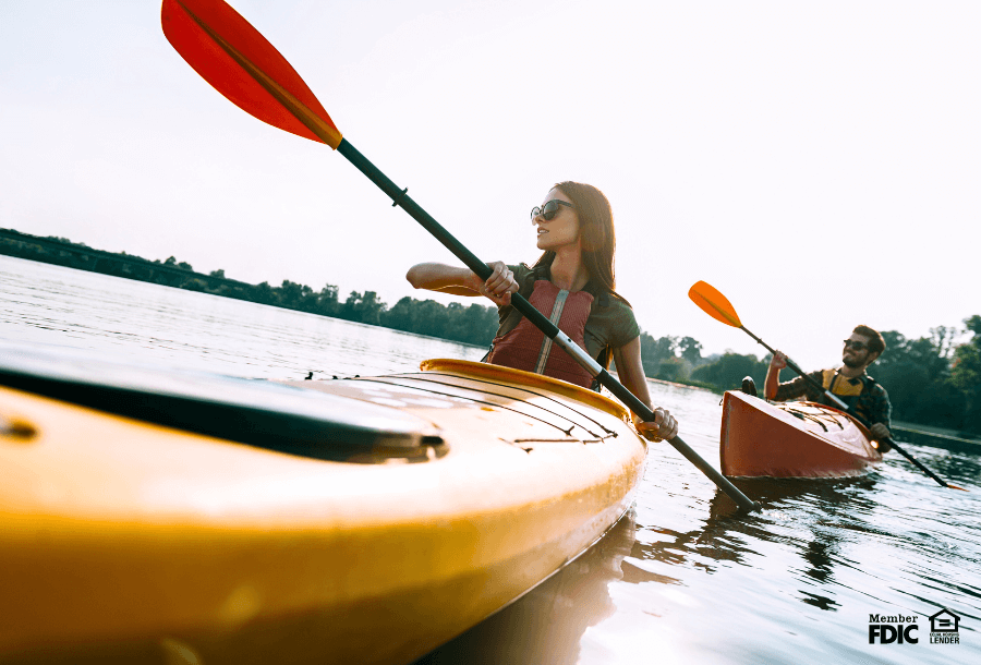 A man and woman enjoy kayaking on a lake. 