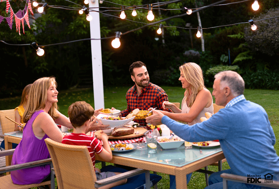 a group of friends gather to have dinner together in their backyard living space financed by a HELOC.  