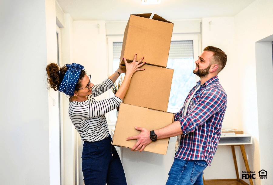 a couple moves boxes into their new rental home on move-in day, financed by a personal loan.